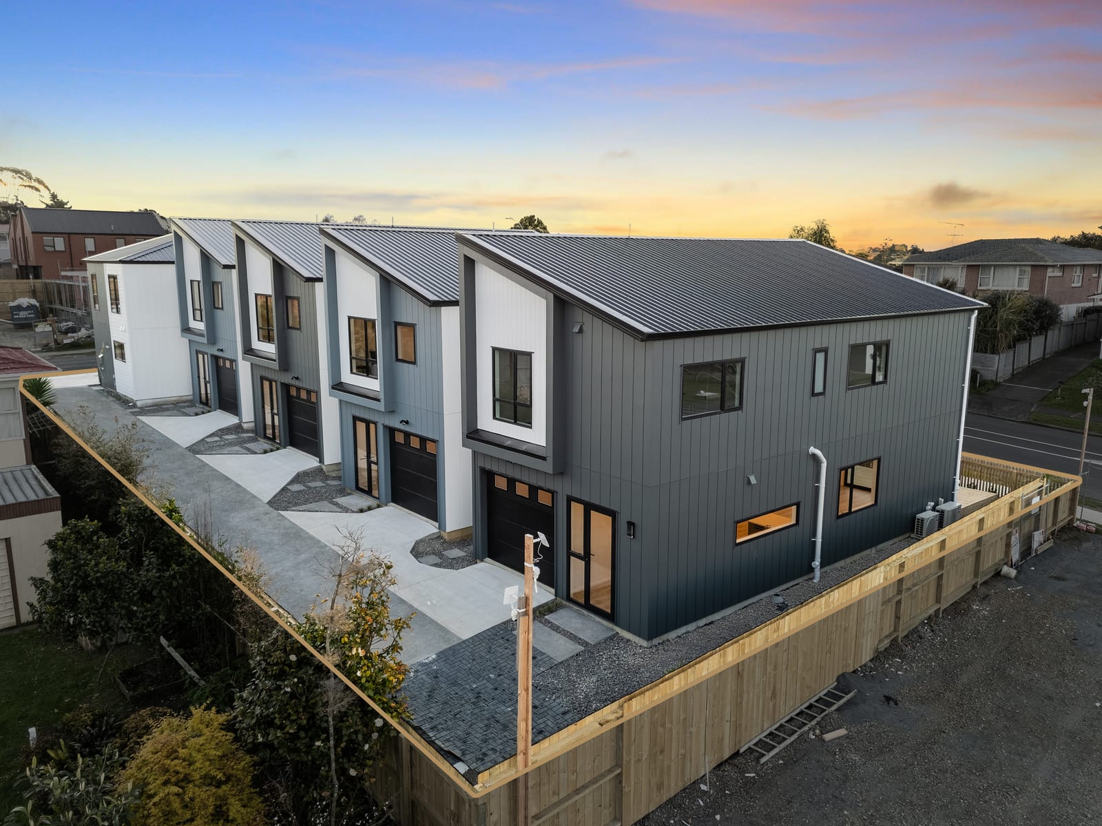 Aerial view at dusk of the five homes with the site boundary outlined