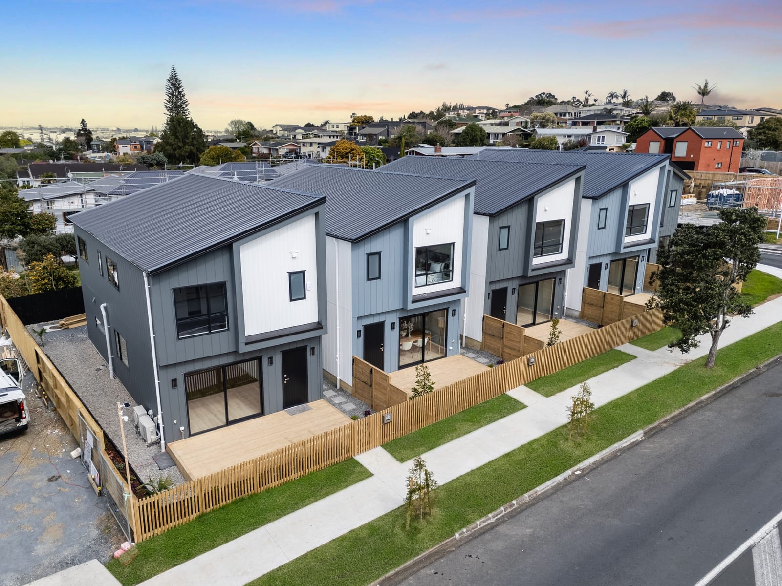 Elevated view along the five homes and the street, with the rooftops of Pakuranga Heights beyond