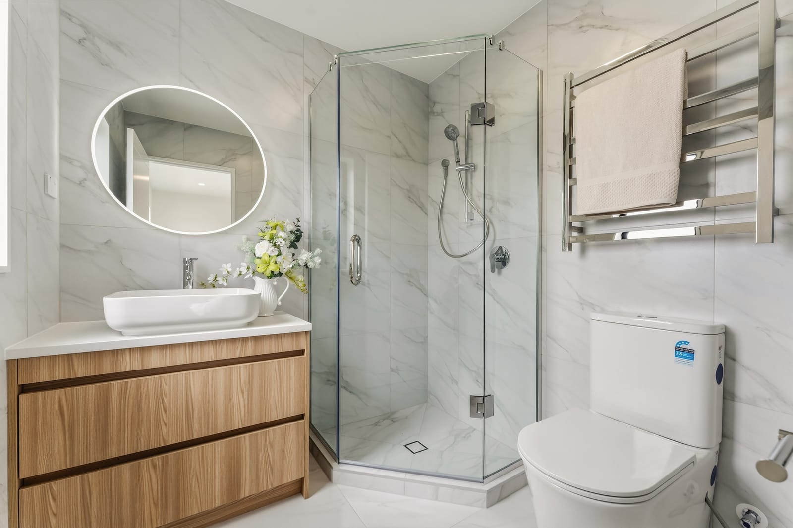 Bathroom with a vessel basin on a timber vanity, backlit mirror and glass shower