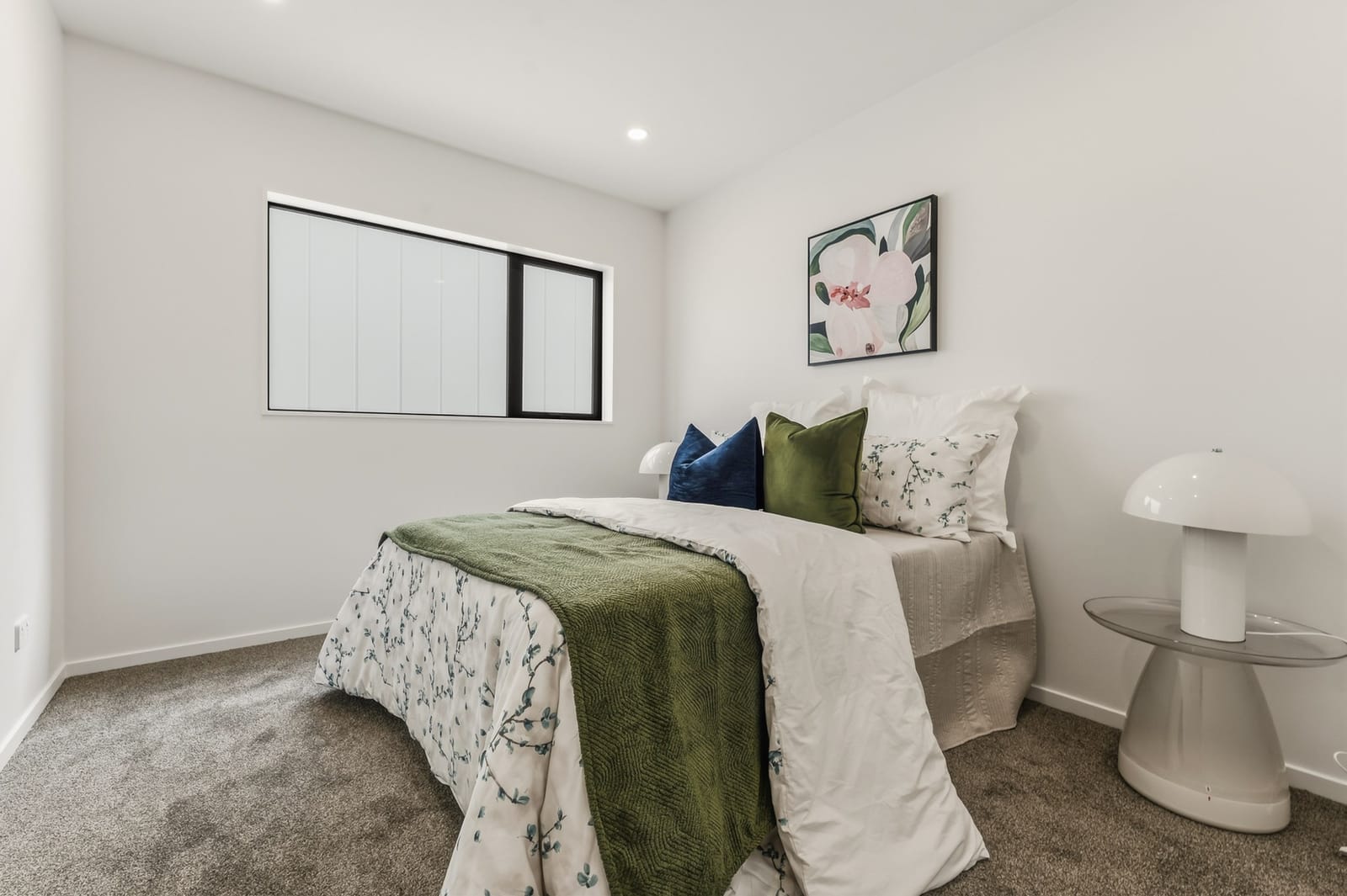 Bedroom with a green throw and a mushroom lamp