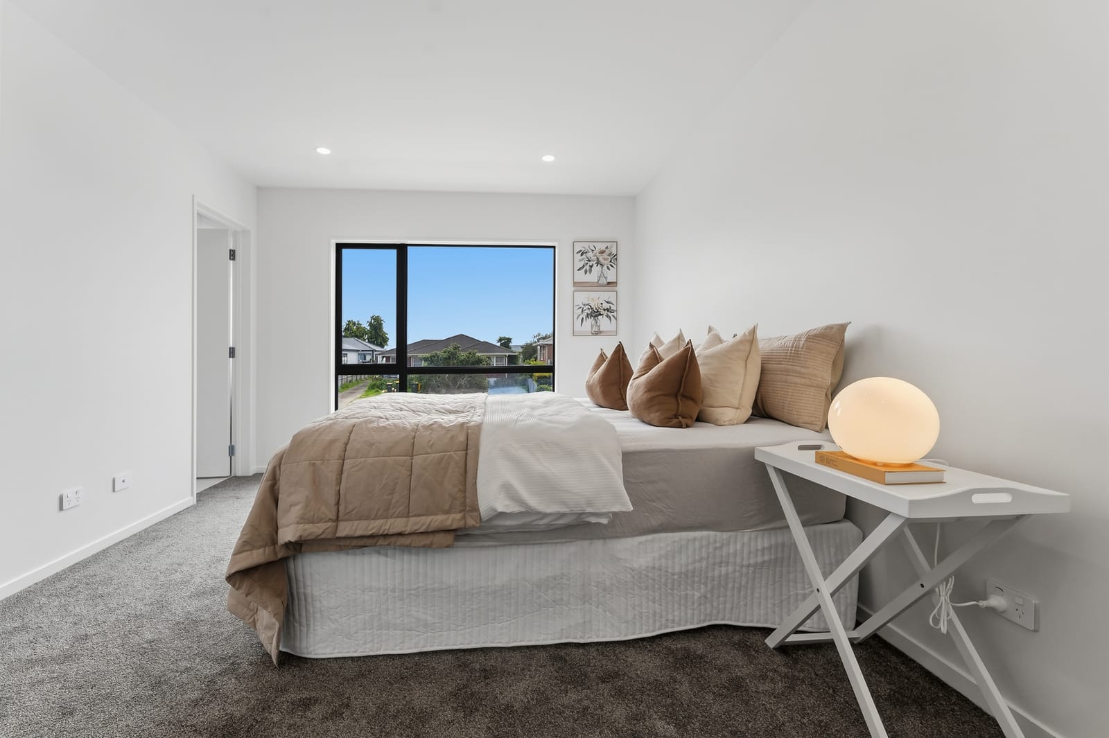 Bedroom with a bedside lamp and a window over the neighbourhood