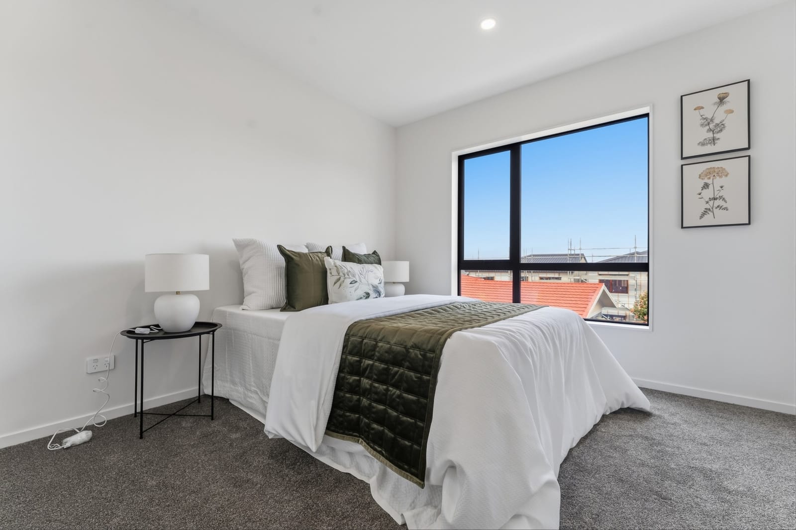 Bedroom with a dark green throw and botanical prints