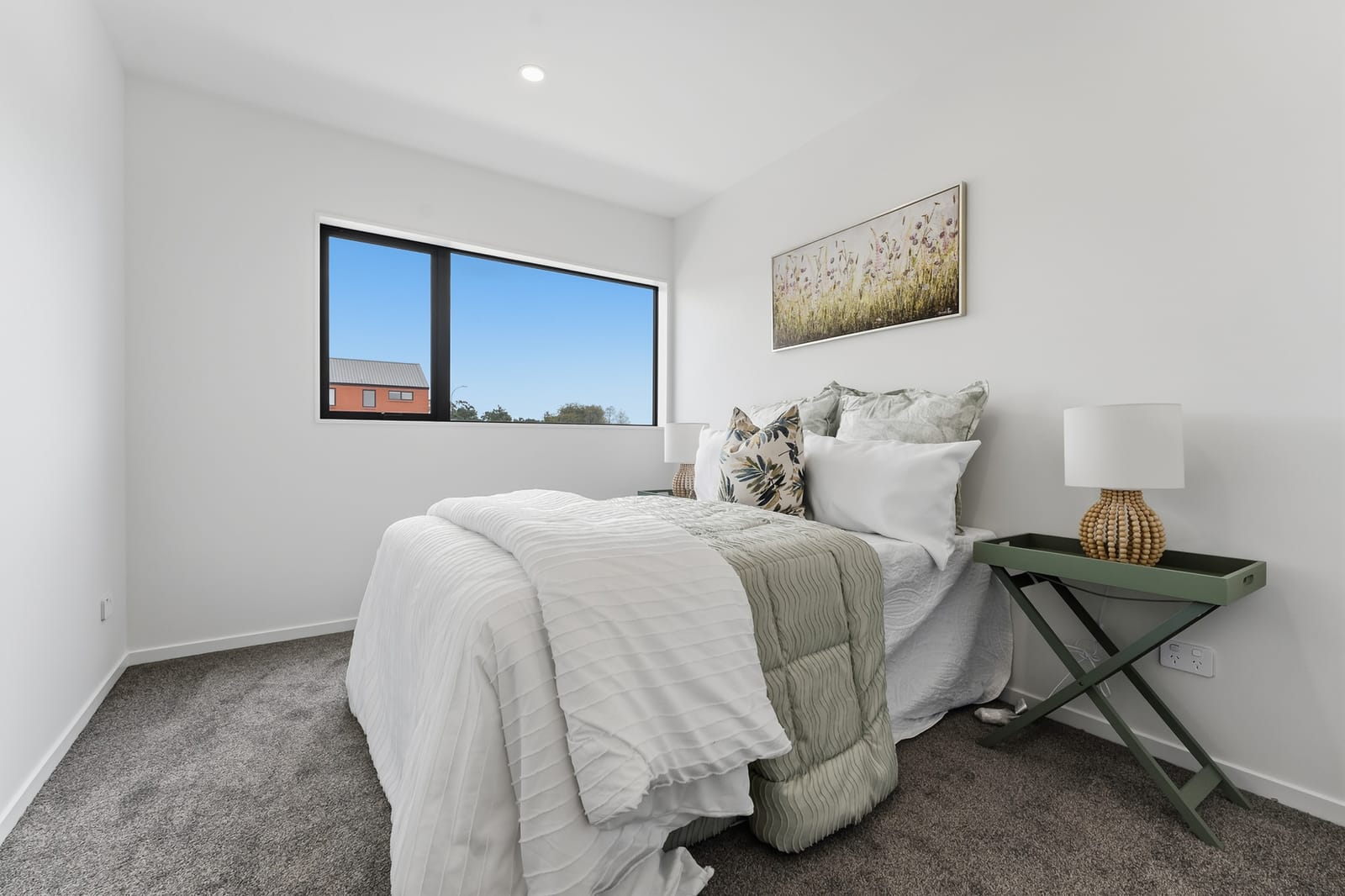 Bedroom with a sage-green side table and a wide window