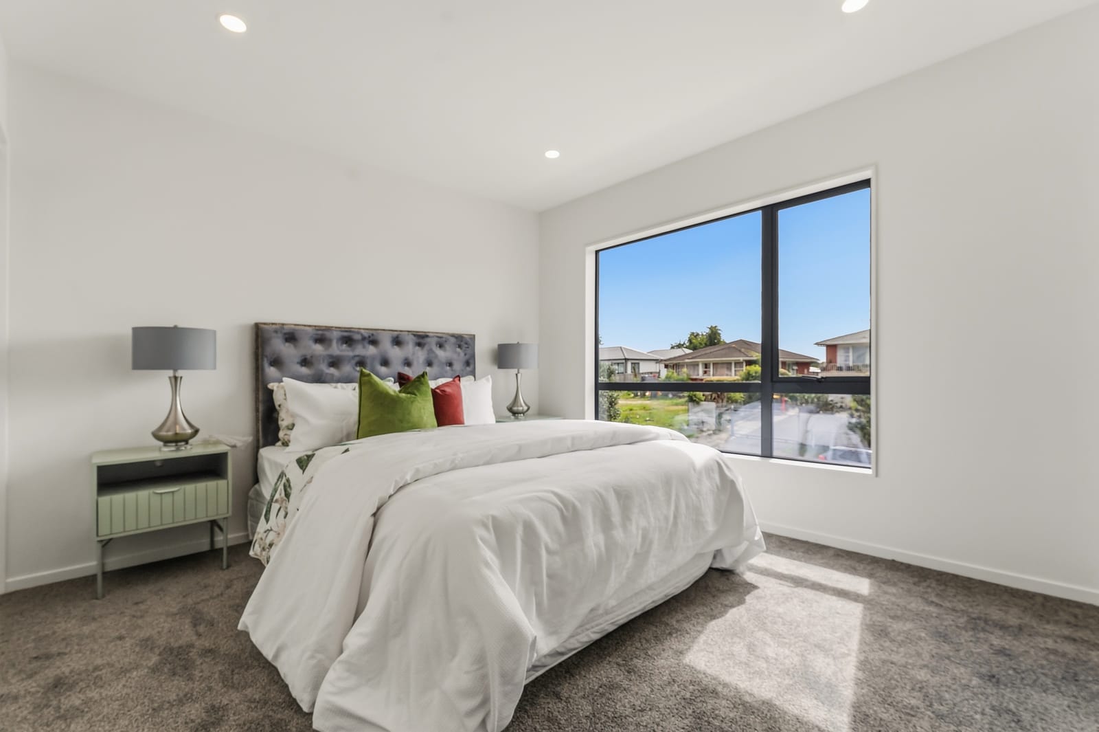 Bedroom with a tufted headboard and a large window