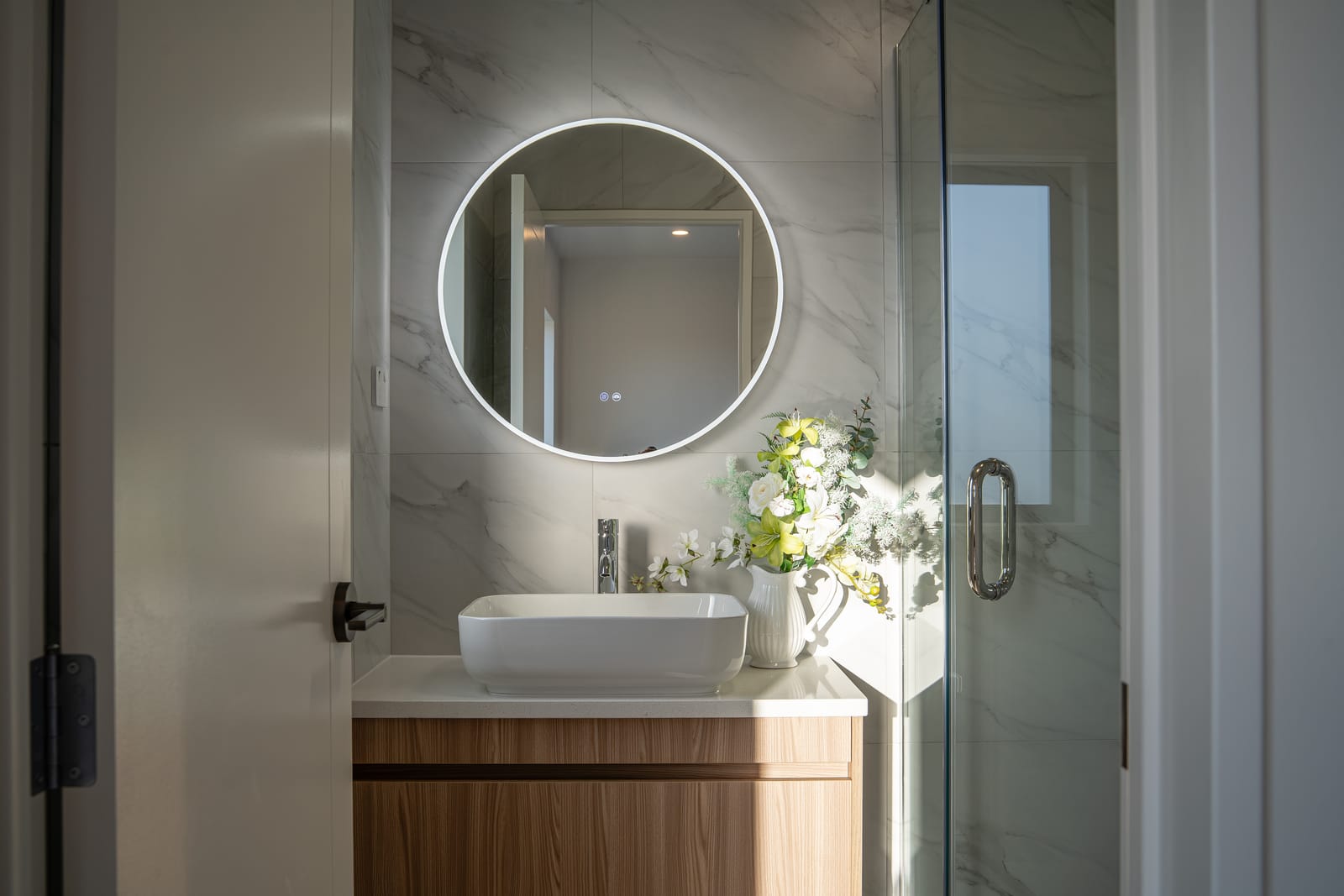 Ensuite with a round backlit mirror and a vessel basin